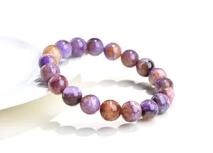 Détail des perles naturelles de charoïte avec texture fibreuse violette et éclat soyeux