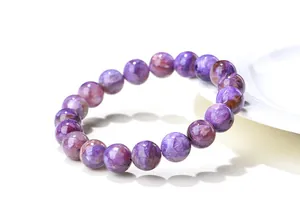Gros plan des perles en charoïte naturelle avec des textures soyeuses violettes et blanches
