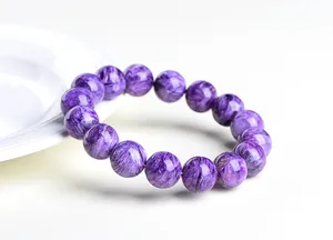 Vue macro de perles en charoïte naturelle de 14mm avec motifs violets et éclat soyeux