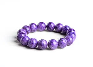 Vue macro des perles rondes en charoïte avec texture violette naturelle et éclat soyeux