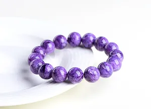 Détail macro de perles de charoïte 12mm montrant une texture soyeuse violette