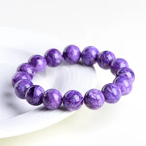 Bracelet de perles de charoïte naturelle violette sur un plateau en céramique blanche