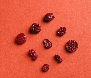 Macro detail of cinnabar charms with koi and rose carvings on orange texture
