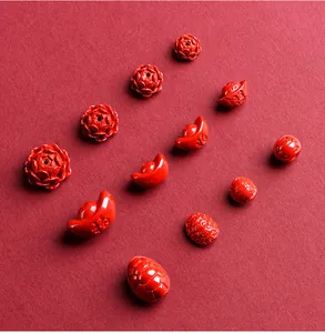 Macro detail of red cinnabar beads in rose, ingot and tortoise shell shapes with Fu character