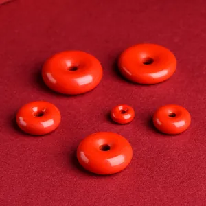 Red cinnabar donut pendants in various sizes on red textured fabric background
