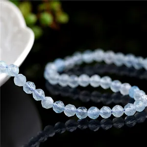 Faceted light blue aquamarine gemstone beads displayed in an S-shape on reflective surface
