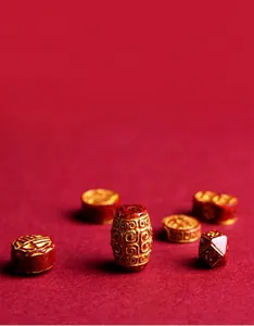 Macro shot of red cinnabar beads with gold engraving and matte texture detail