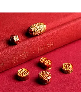 Macro detail of red cinnabar beads with gold engraved Fu character and traditional patterns