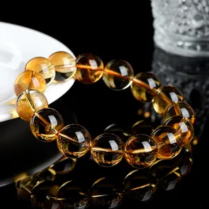 Natural yellow citrine round bead bracelet with transparent crystal texture on black surface