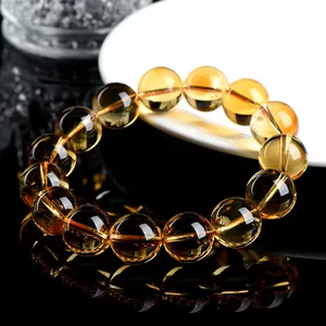 Natural yellow citrine round bead bracelet displayed on a sleek black reflective surface