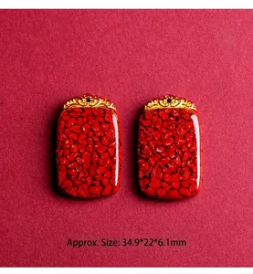Macro detail of red cinnabar rectangular pendants with golden cloud pattern relief