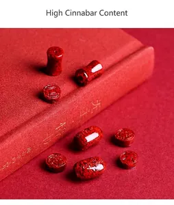 Makroaufnahme roter Zinnober-Kristallsandperlen mit Wolkenmuster auf antikem Buch