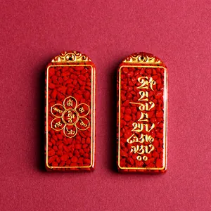 Cinnabar peace amulet pendants with gold trim and sacred mantras on red background