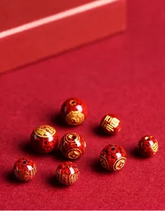 Macro detail of red cinnabar beads with gold engraved traditional Chinese symbols