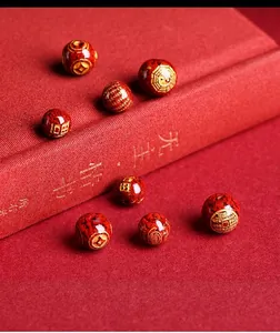 Macro detail of cinnabar crystal sand beads with gilded Bagua and Chinese fortune symbols