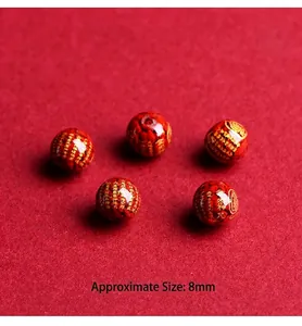 Macro detail of 8mm red cinnabar beads with gold engraved sacred scriptures and mantras