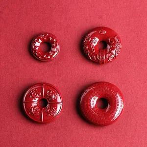 Four red cinnabar pendants with lotus, dragon, and cloud engravings in a circular design