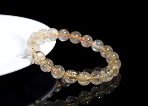 Macro view of golden rutilated quartz beads with visible needles and clear reflection