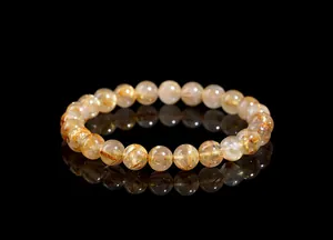Macro shot of natural gold rutilated quartz beads showing dense golden rutile inclusions