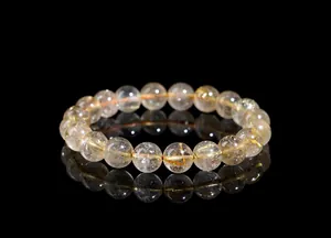 Macro shot of natural gold rutilated quartz bracelet with golden needle inclusions