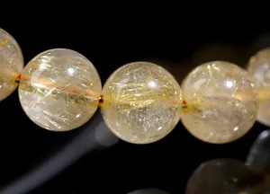 Macro shot of natural golden rutilated quartz beads with metallic needle inclusions