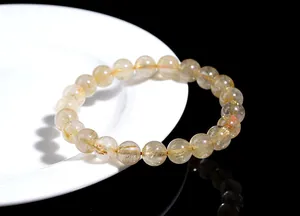 Macro detail of natural rutilated quartz bracelet with golden hair needles on ceramic