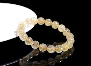 Detailed shot of natural golden rutilated quartz beaded bracelet with red elastic cord