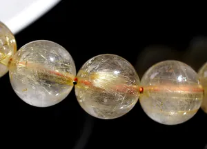 Macro shot of natural golden rutilated quartz beads showing dense needle-like inclusions
