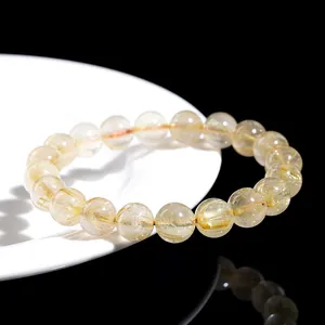 Natural golden rutilated quartz bead bracelet displayed on a white ceramic plate