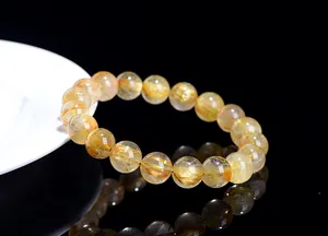 Close-up of natural rutilated quartz bracelet with golden hair-like inclusions on black surface