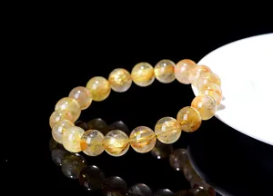 Macro detail of high-quality gold rutilated quartz beaded bracelet with metallic inclusions