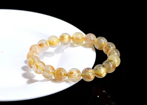 Macro shot of Gold Rutilated Quartz bracelet with dense golden needles on ceramic plate