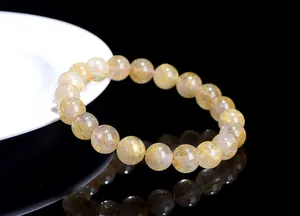 Macro shot of 12mm golden rutilated quartz crystal bracelet with visible golden needles