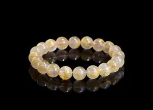 Macro shot of natural golden rutilated quartz crystal beads showing fine golden needles