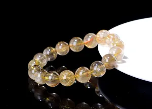 Macro shot of natural gold rutilated quartz bracelet with dense golden needle inclusions
