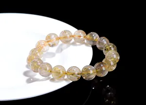 Close-up of natural golden rutilated quartz beaded bracelet on a white ceramic plate