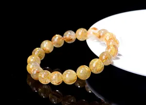 Macro detail of natural rutilated quartz bracelet featuring dense golden crystal inclusions