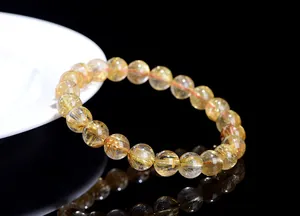 Macro shot of natural gold rutilated quartz bracelet showing dense golden needle inclusions