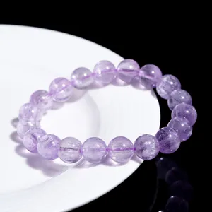 Natürliches lila Kunzit-Perlenarmband mit Katzenaugeneffekt auf weißer Keramik präsentiert