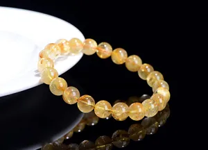 Macro shot of natural rutilated quartz bracelet with golden needle inclusions on black surface