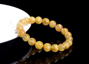 Macro shot of natural gold rutilated quartz bracelet beads with needle inclusions