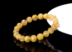 Macro detail of natural golden rutilated quartz bracelet showing needle-like inclusions
