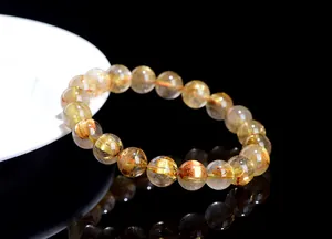 Macro shot of high-quality golden rutilated quartz bracelet on black reflective surface