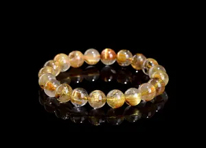 Detailed close-up of golden rutilated quartz bracelet with dense metallic needle inclusions