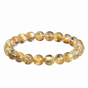 Natural golden rutilated quartz bead bracelet with golden needle inclusions on white background