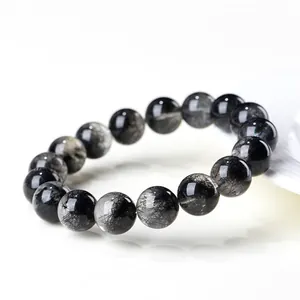 Pulsera de cuentas de cuarzo rutilado negro natural de grado 7A en un plato de cerámica blanca