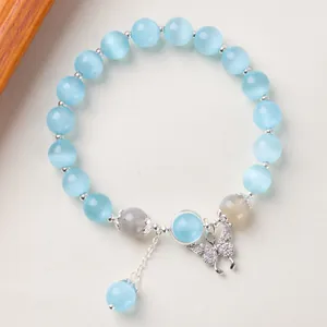 Détail de perles en œil de chat bleu avec un pendentif papillon en argent délicat