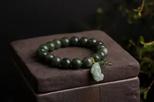 Macro view of dark green jade beads and a light green Pixiu charm on a stone stand