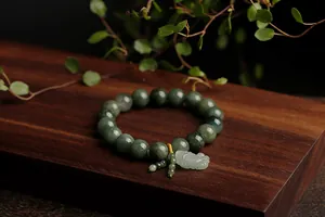 Close-up of green jade beads with a carved PiXiu charm and handmade knot details