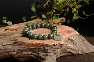 Detail of natural green jade beads and Pixiu pendant on a Zen wooden background